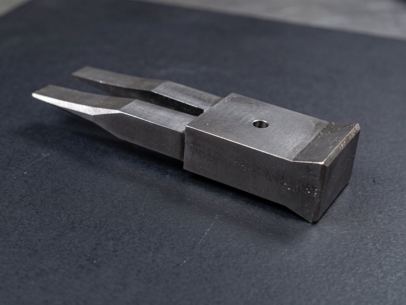 förk, machined steel, on a dark bench